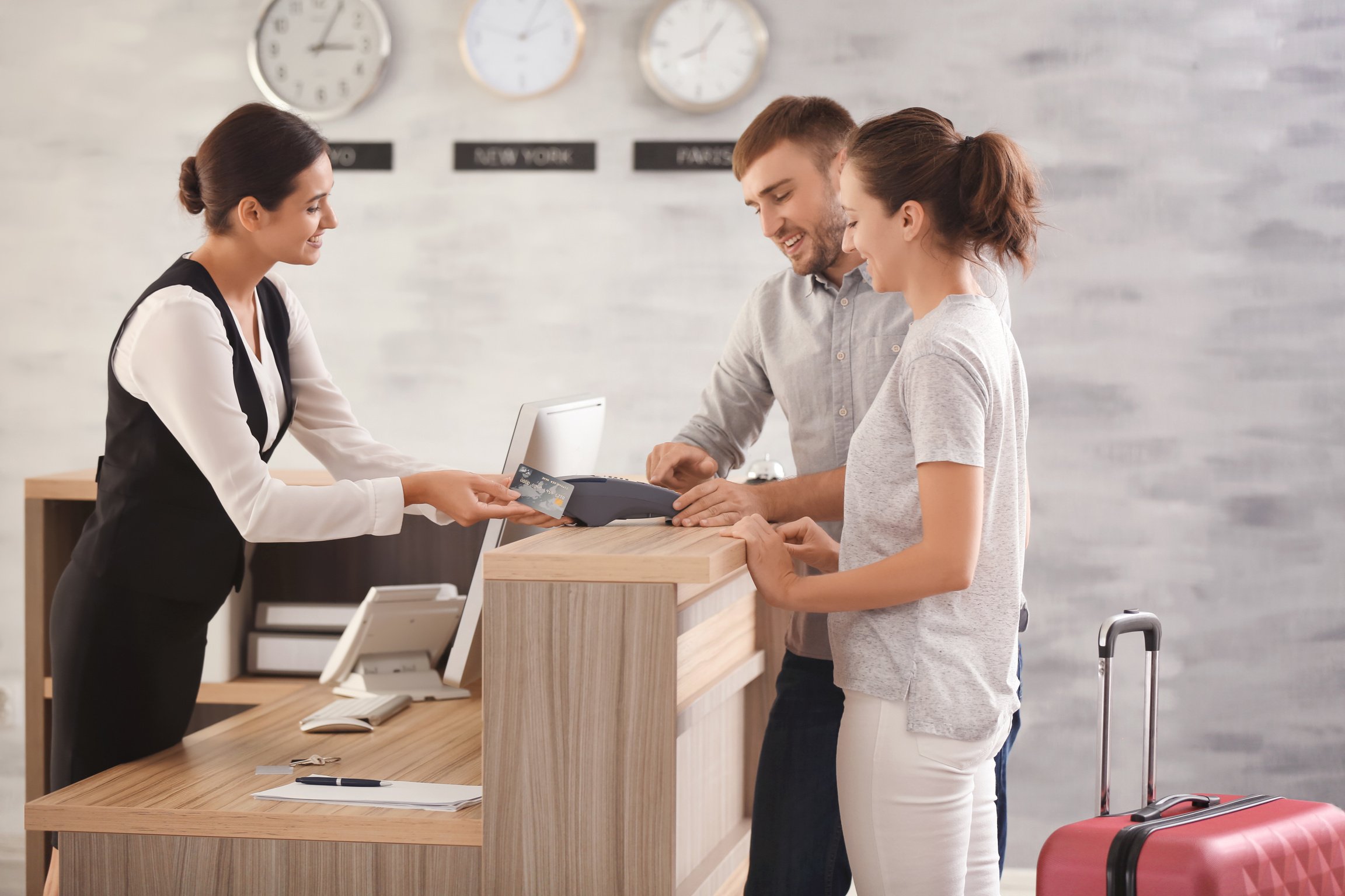 Young Couple Paying for Hotel Room at Reception